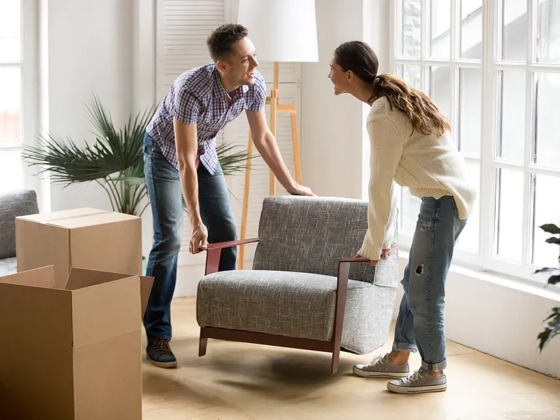Couple moving an armchair to prepare for flooring install