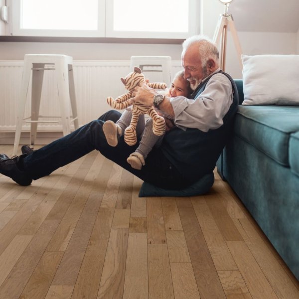 Child and grandfather playing on a hardwood floor in a family home